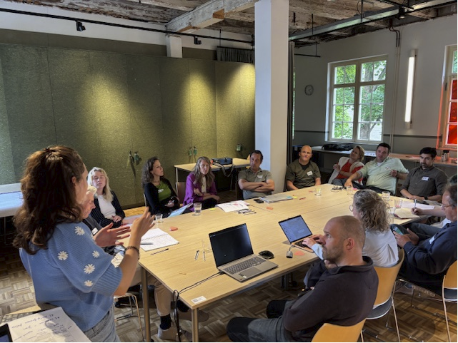 Workshop sessie in moderne vergaderruimte met deelnemers rond de tafel